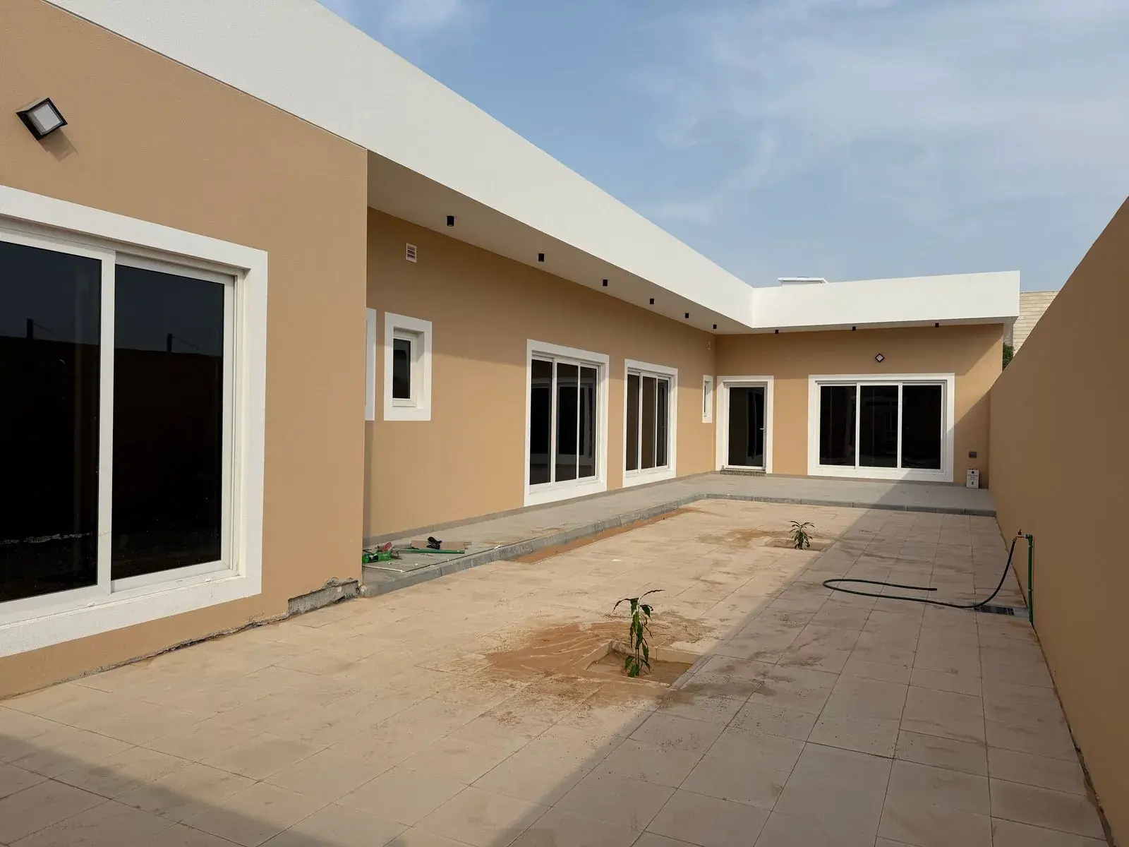 Villa courtyard with sand-coloured walls and sliding windows