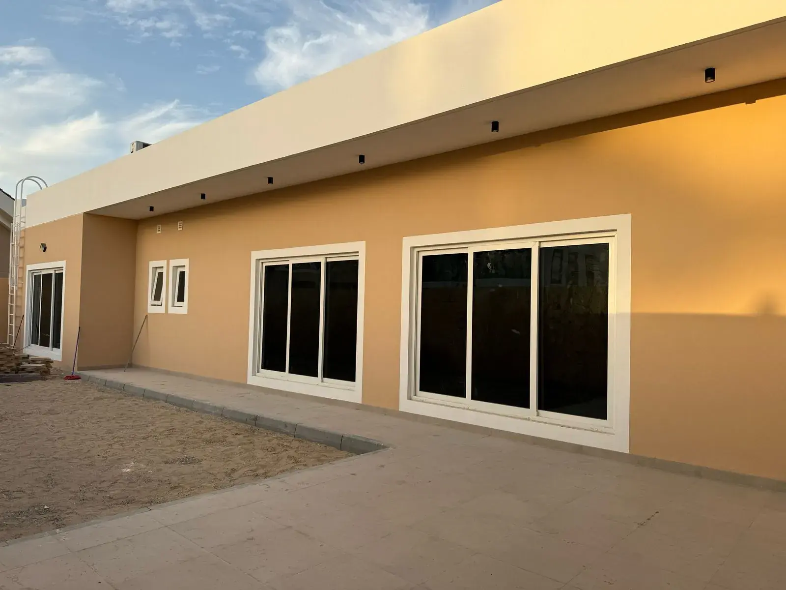 Villa exterior with sand-coloured walls and white window frames
